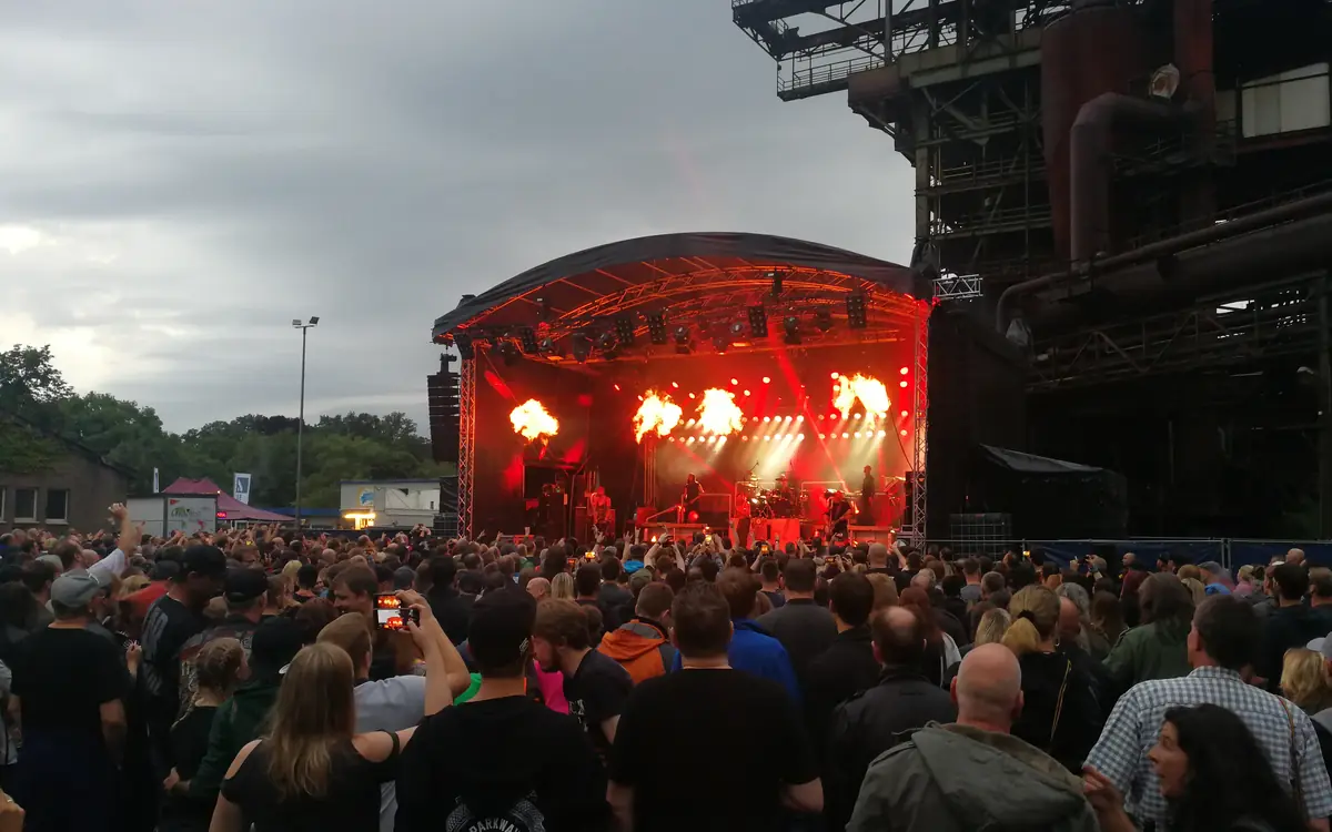 Konzert mit Pyrotechnik vor einer Industriekulisse, im Vordergrund das Publikum