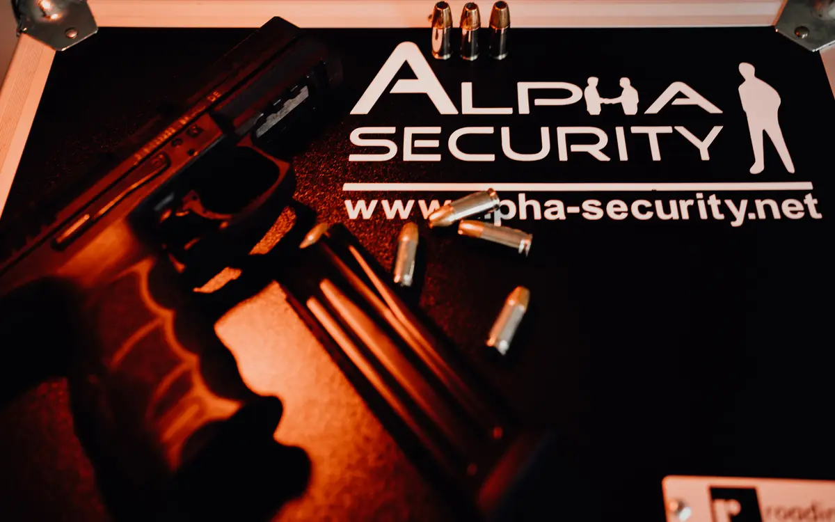 Pistole und Munition auf einem Koffer mit dem Alpha-Security-Logo