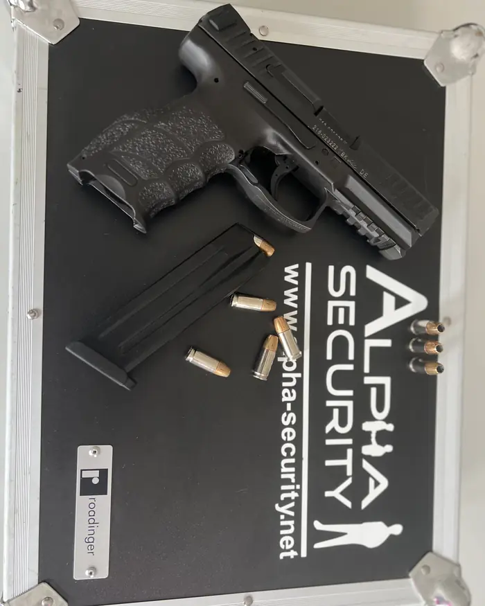 Dienstpistole, Magazin und Munition auf einem Koffer mit Alpha-Security-Logo